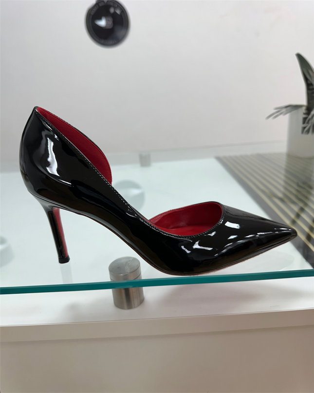 Black patent leather high-heeled shoe with a red sole.