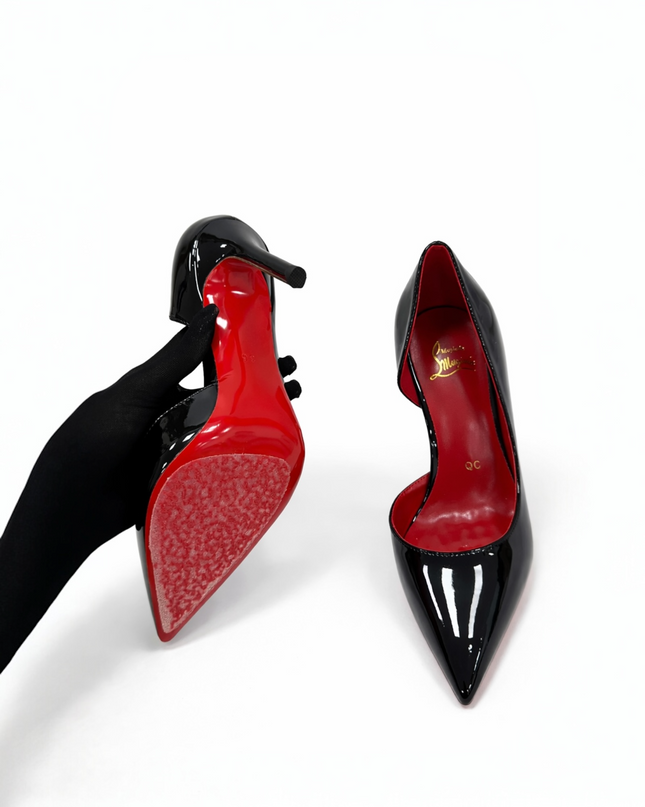 Black patent leather high-heeled shoe with a red sole.